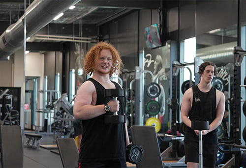 Two people lifting dumbbells in a gym
